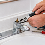 Hands removing a faucet handle to access the cartridge for replacement